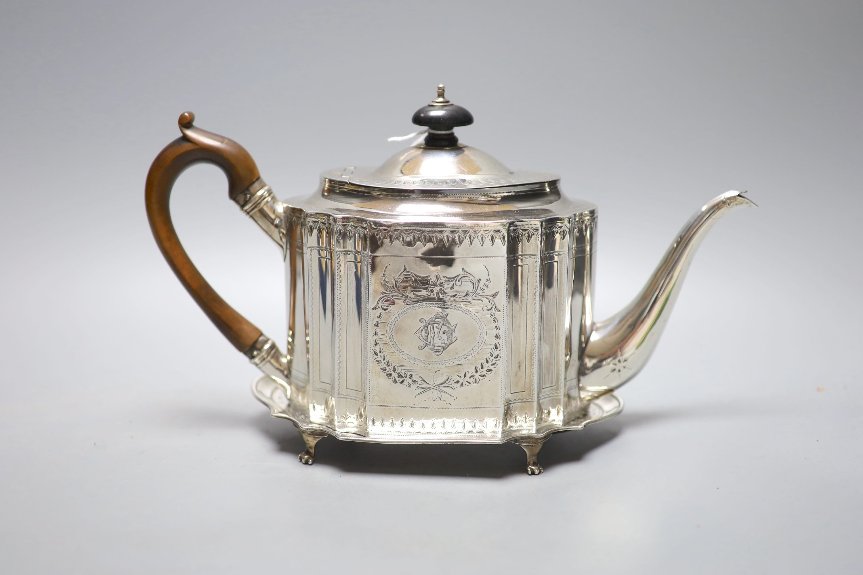 A George III bright cut engraved oval teapot and matching stand, Soloman Hougham, London, 1794, stand 19.3 cm, gross 20oz.